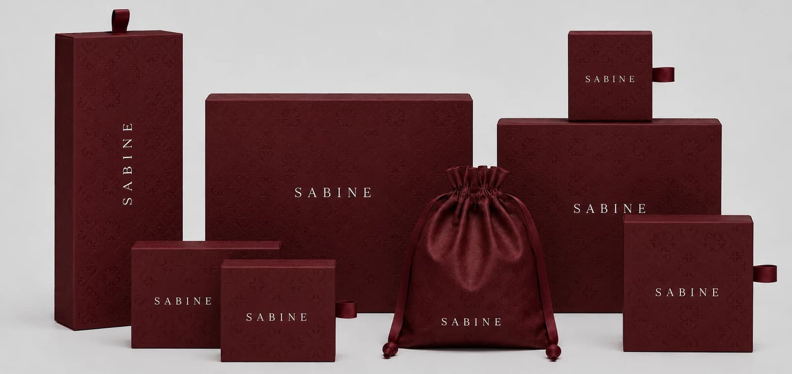 Embalagens Sabine em caixas e bag vinho com acabamento em relevo